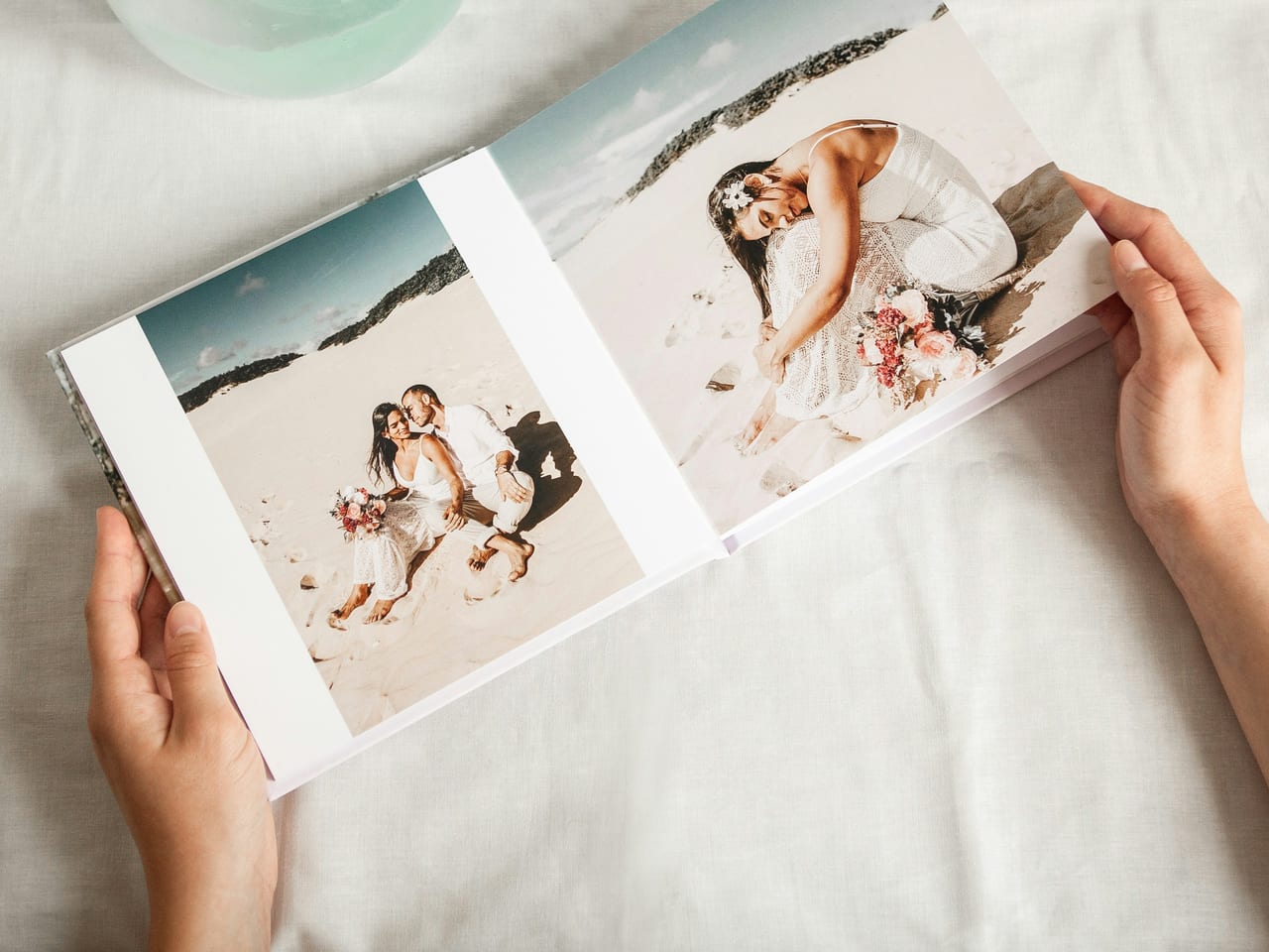 Hands holding an open wedding photo book showing two carefully chosen moments