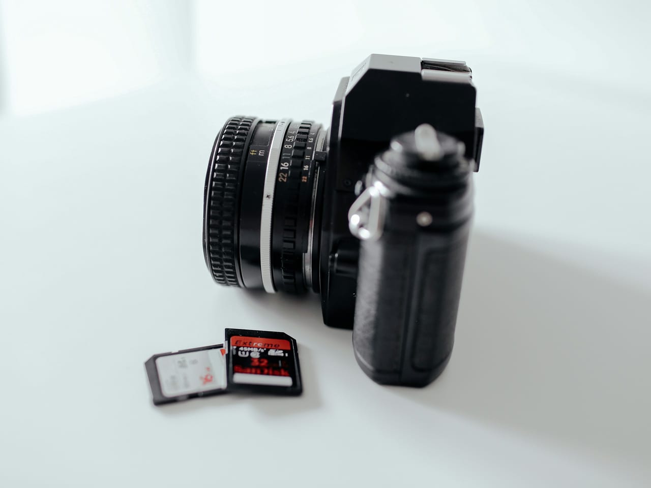 Camera and two memory cards on a white surface